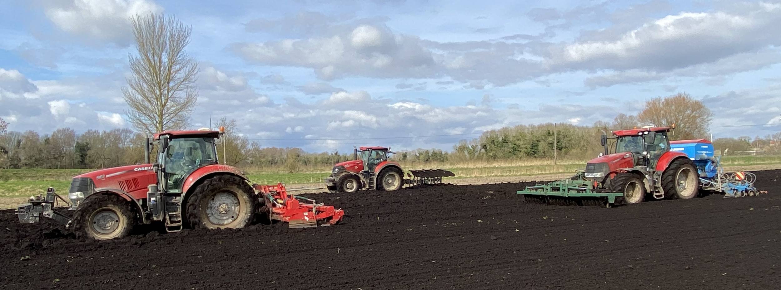 Glover 3 red tractors cultivating filed.
