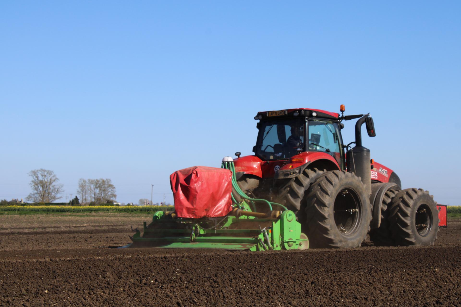 Glover red tractor working in the field for seed bed preparation