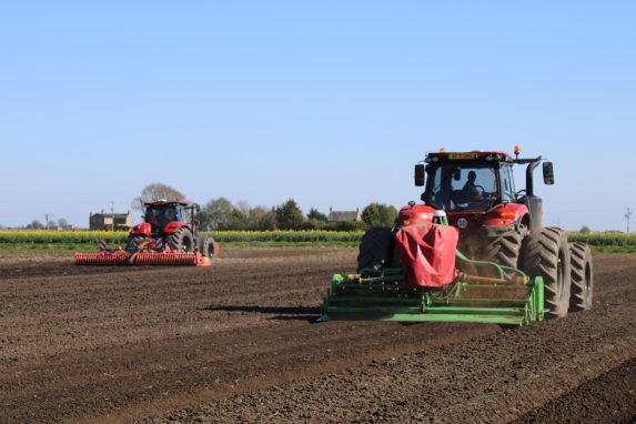 2 red tractor working on seed bed preparation in field